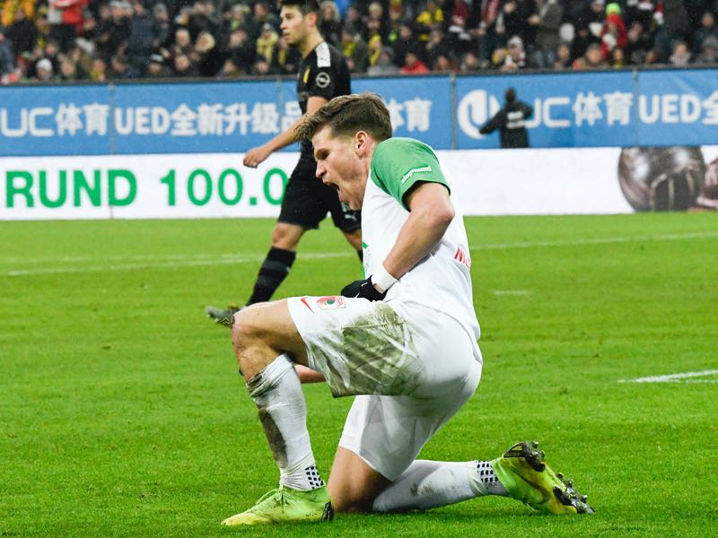 Augsburg v Dortmund - Augsburg's German forward Florian Niederlechner (C) reacts after he scored the 1-0 past Dortmund's Swiss goalkeeper Roman Buerki and German defender Mats Hummels (L) during the German first division Bundesliga football match Augsburg v Borussia Dortmund in Augsburg, on January 18, 2020. (Photo by THOMAS KIENZLE / AFP)